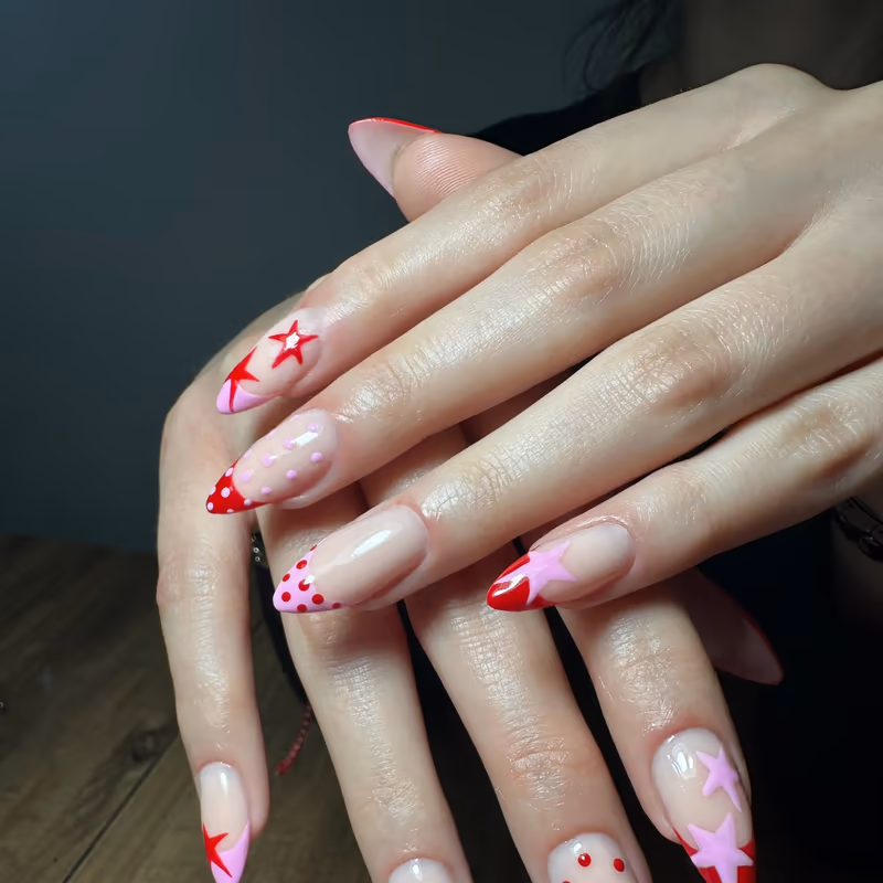 Long almond nails with red and pink hand-painted star nail art